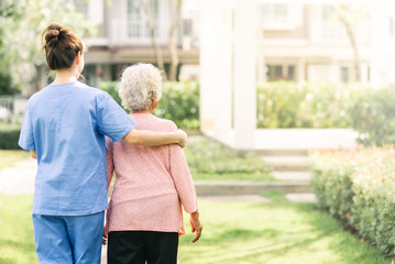 nurse caregiver support walking with elderly woman outdoor
