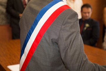 French mayor in grey suit with a scarf flag during a weeding day