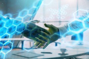 Multi exposure of tech theme hologram on office background with two men handshake. Concept of technology