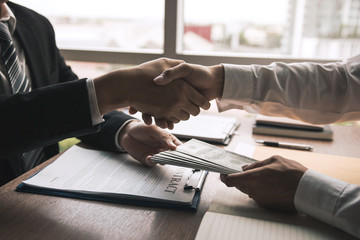 Two corporate businessmen shaking hands while one man giving money and receive cash dirty in office...