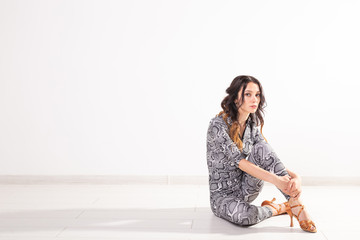 Latino dance, Improvisation, contemporary and vogue dance concept - young beautiful woman dancer sitting on white studio background