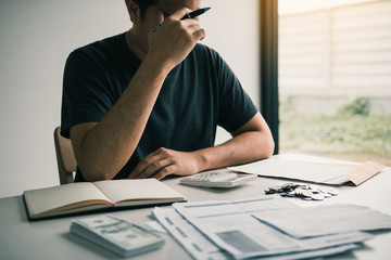 Asian men are stressed about financial problems, with invoices and calculators placed on the table...