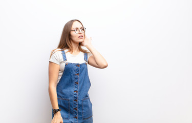 young pretty woman looking serious and curious, listening, trying to hear a secret conversation or...