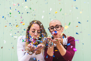 Two Girl Friends Blowing Confetti Outdoors.
