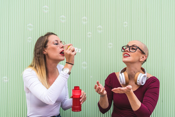 Two Friend Girls Playing with Soap Bubble Outdoors.