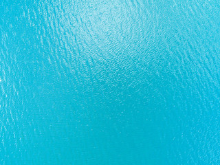 Naklejka na ściany i meble Aerial view of a Crystal clear sea water texture. View from above Natural blue background. Turquoise ripple water reflection in tropical beach. Blue ocean wave. Summer sea. Drone. Top view