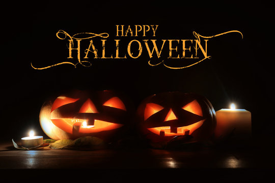 holidays image of halloween. Pumpkins over wooden table dark background