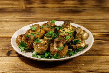 Baked mushrooms in plate on wooden table