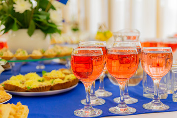 Festively laid tables at the Banquet. Various delicacies, snacks and drinks. Catering. Pink wine in glasses.