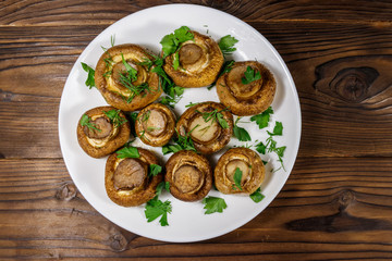 Baked mushrooms in plate on wooden table. Top view