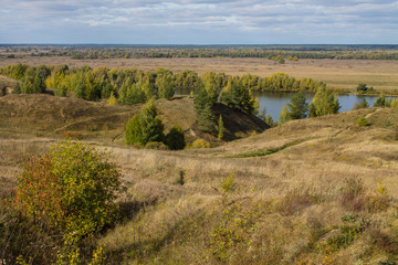 Fototapeta na wymiar Autumn panoramic landscape with river and hills cloudy day in Konstantinovo village Russia