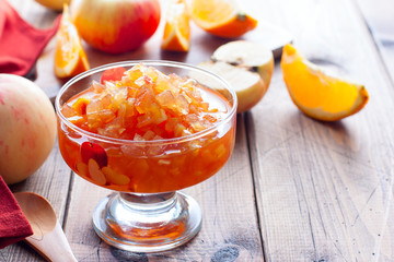 Fruit jam from apples and oranges in a glass vase on a wooden table, horizontal, copy space