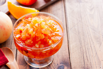 Fruit jam from apples and oranges in a glass vase on a wooden table, horizontal, copy space