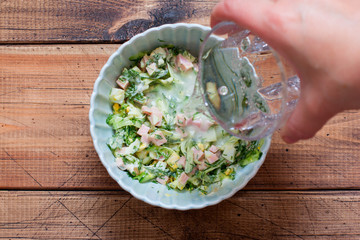 Step by step cooking traditional Russian cold okroshka soup, step 4 adding mineral water, top view, horizontal