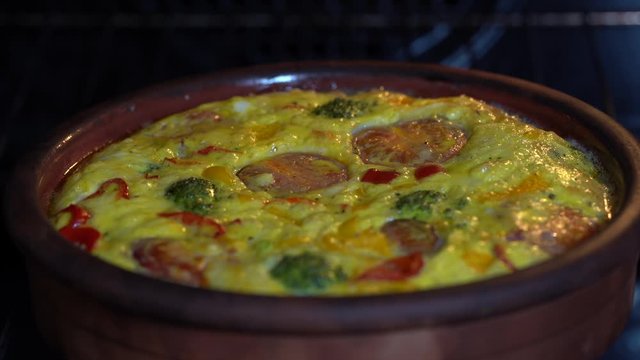 Ceramic bowl with vegetable frittata, simple vegetarian food. Frittata with egg, tomato, pepper, onion, broccoli and cheese , close up. Italian egg omelette in oven