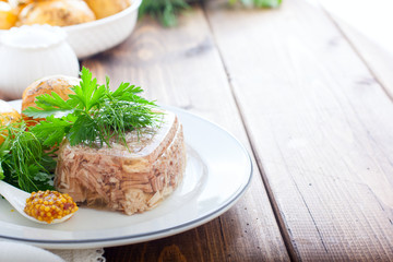 Homemade Aspic of turkey meat on a white plate with boiled potatoes and fresh herbs, horizontal, place for text