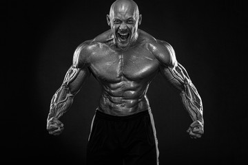 Fototapeta na wymiar Bodybuilding competitions on the scene. Handsome and fit man sportsmen bodybuilder physique and athlete. Men's fitness motivation. Black and white photo.