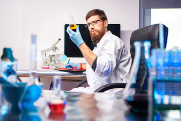 Computer, microscope and chemical utensils are in the laboratory. The scientist visually assesses the result of the experiment. The chemical liquid changed color after the reagent was added.