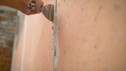 Construction worker with long trowel plastering a wall. Putty walls