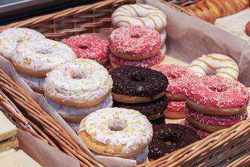 lots of doughnuts close up on in a wooden box on the counter at the bakery. fresh, delicious pastries