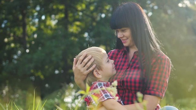 happy family mom and son concept .lifestyle mom tender childhood video . slow motion video .mom brunette girl gently hugs takes care of the boy a son blonde outdoors