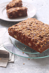 Vegan Square Chocolate Cake with Apples and Walnuts, on a plate, on a grey background.