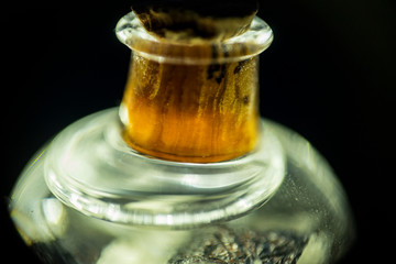 Small bottle of liquid with a tiny cork seen in macro and isolated on black.
