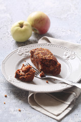 Vegan Square Chocolate Cake with Apples and Walnuts, on a plate, on a grey background.
