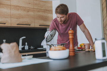 Young cook carefully preparing food for dinner