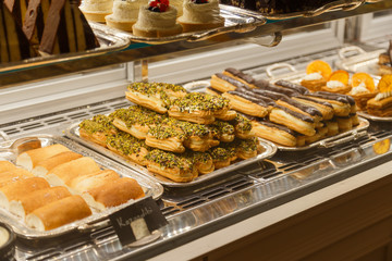 Eclairs and other sweets on showcase at cafe.