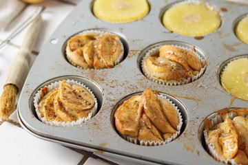 Muffins cupcakes with pineapple circles and apple slices in a cupcake muffin tray, on kitchen white tile near with pastry brush. Cake dessert photo for cook book recipe top view