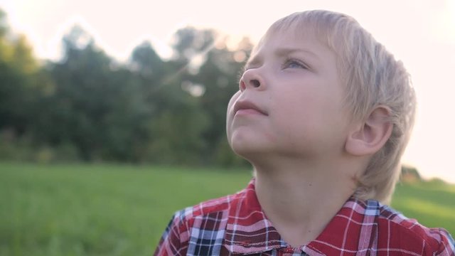 little boy portrait concept happy family. boy blond son looking up portrait slow motion video in nature in a plaid shirt sunlight glare happy childhood lifestyle concept