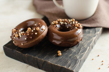 Chocolate donuts with glaze and crispy balls on dark wooden board