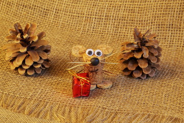 Fototapeta na wymiar Charming homemade mouse made of natural wine cork with gift and large fir cones on jute coarse homespun cloth. Concept - New Year, symbol of 2020, holiday, greeting background. Handmade.