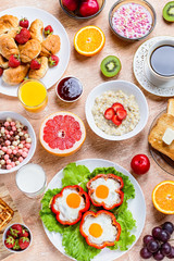 Continental breakfast with cereal, fried eggs, croissants, fruits and drinks on textured table, copy space