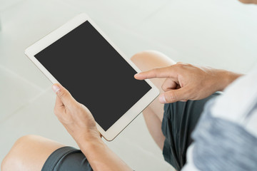 Young man is relaxing on comfortable couch and using tablet at home.