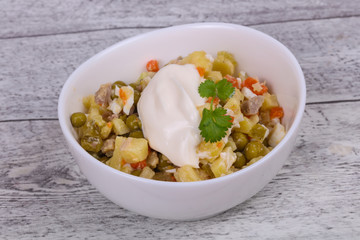 Traditional Russian salad with chicken in the white bowl