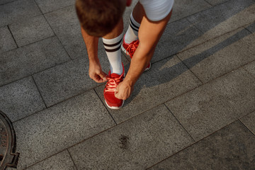 Male athlete bending over his untied shoelace