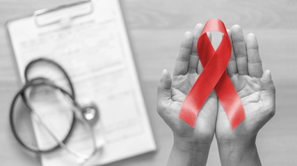World aids day and national HIV/AIDS and ageing awareness month with red ribbon on woman hand support (bow isolated with clipping path) - obrazy, fototapety, plakaty