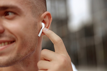 Smiling handsome man with a wireless earphone