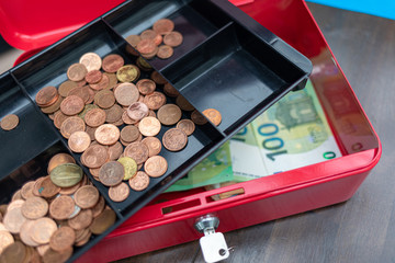 a lot of euro banknotes lie spread out in a red cash box