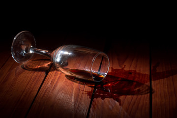 Alcohol addiction, depression. Overturned glass of wine on a wooden table.