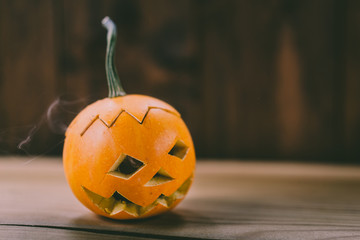 Closeup Photo of Small Carved Pumpkin on the dark Wooden Background with place for text