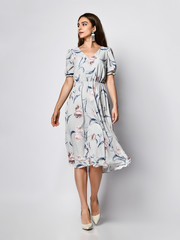 Slim curly female model in a silk pale pink dress looking at the camera in full growth. Cute girl...