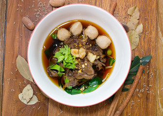Pork noodles arranged in a bowl on a wooden table.