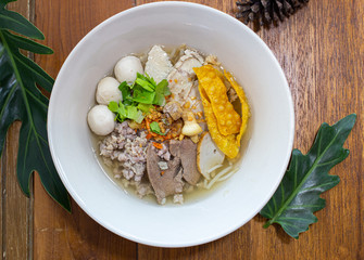 Pork noodles arranged in a bowl on a wooden table.