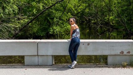 Woman standing on bridge near Swampy river off highway in Virginia