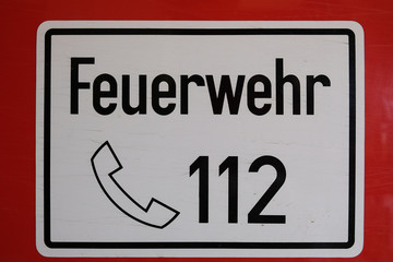 German fire brigade sign with lettering "Feuerwehr" - fire department and german emergency number 112