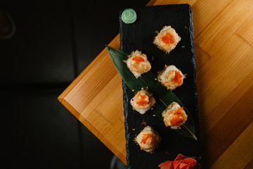 Sushi rolls with salmon and hot tea ceremony on wooden table
