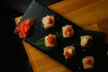 Sushi rolls with salmon and hot tea ceremony on wooden table